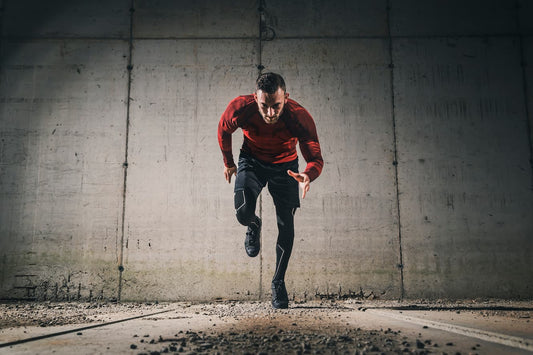 Man sprinting on concrete with intense focus and determination, against a dark background