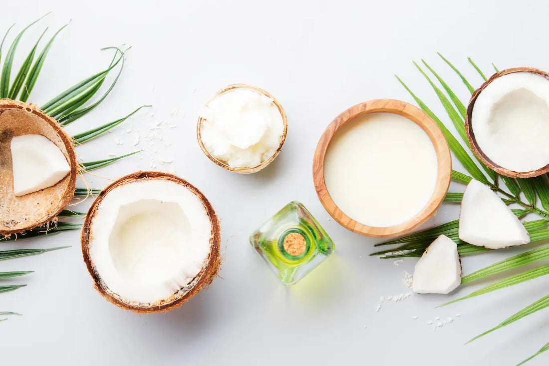 Image of coconuts, coconut oil and coconut milk on a concrete table, showcasing the use of coconuts in various forms in food and health products.