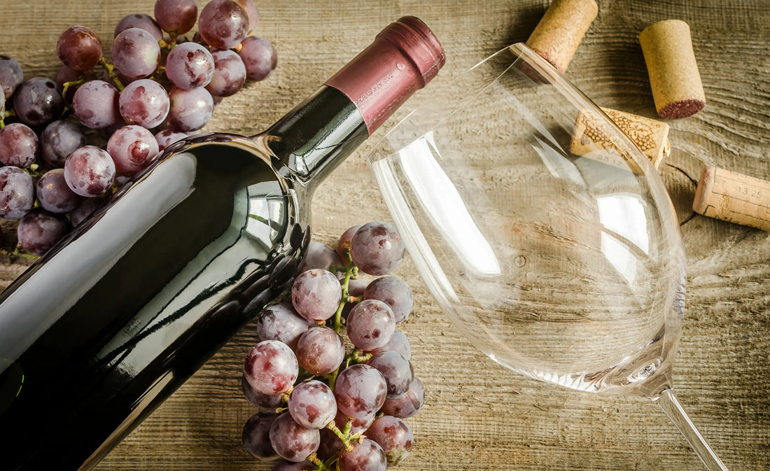 A bottle of red wine, an empty glass, and grapes on a wooden table - Image representing potential health benefits of resveratrol found in red wine and grapes