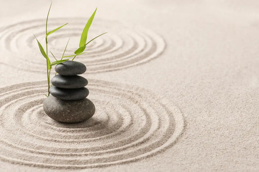 Image of stacked rocks in a zen garden with green leaves - a symbol of balance, harmony, and tranquility